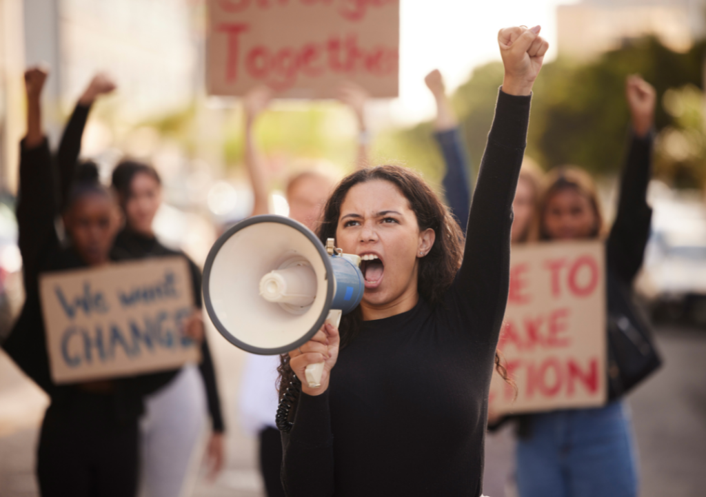 Woman, Megaphone and Fist in Community Protest for Change, Gender Based Violence or Equality in the City.